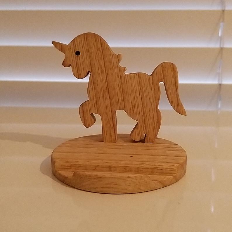 Wooden unicorn figurine on a round base against a neutral background