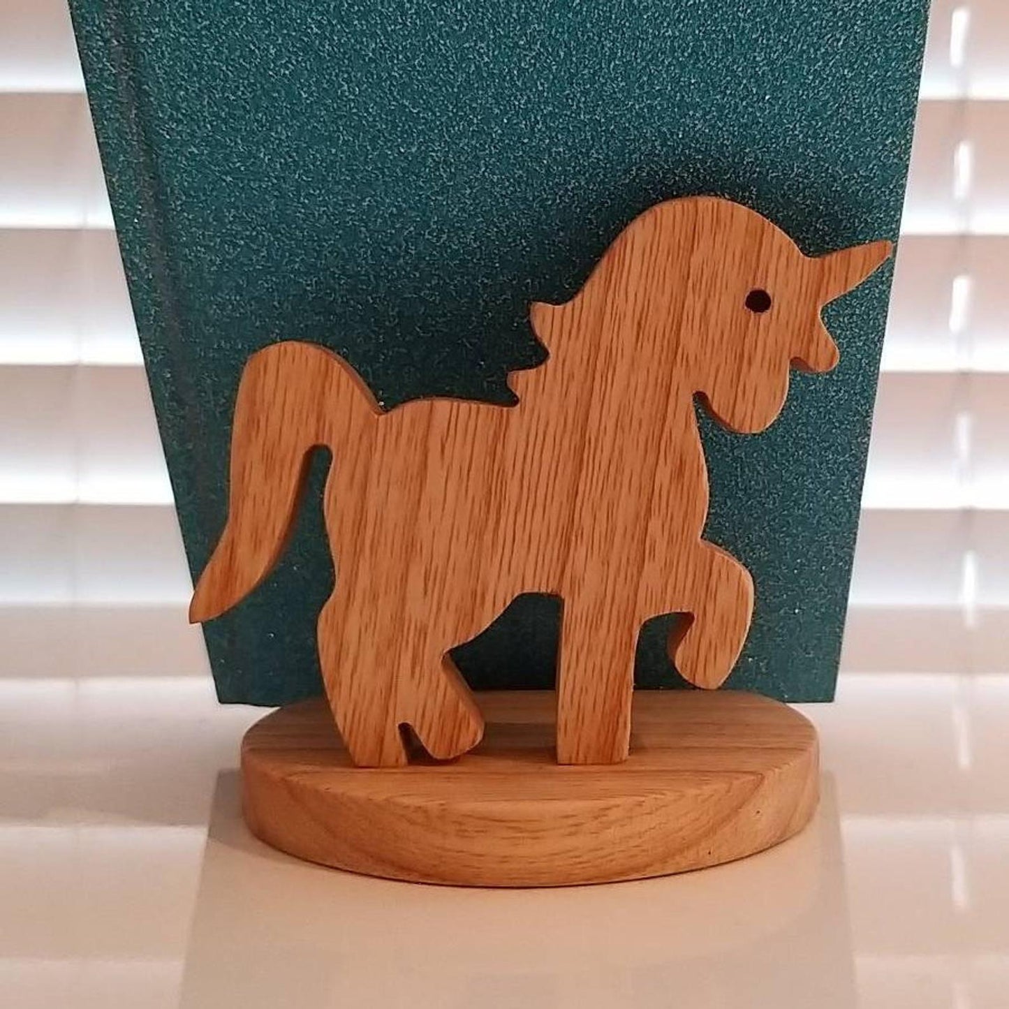 Wooden unicorn figurine on a round base against a green textured background