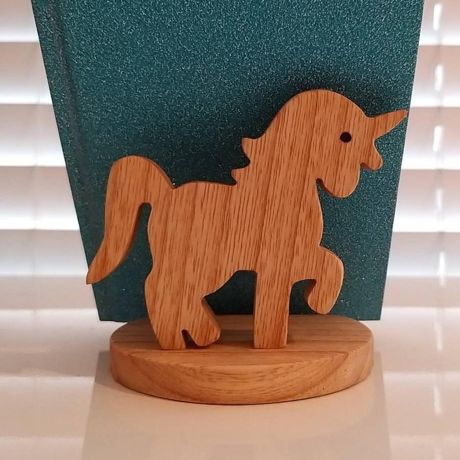 Wooden unicorn figurine on a round base against a green textured background