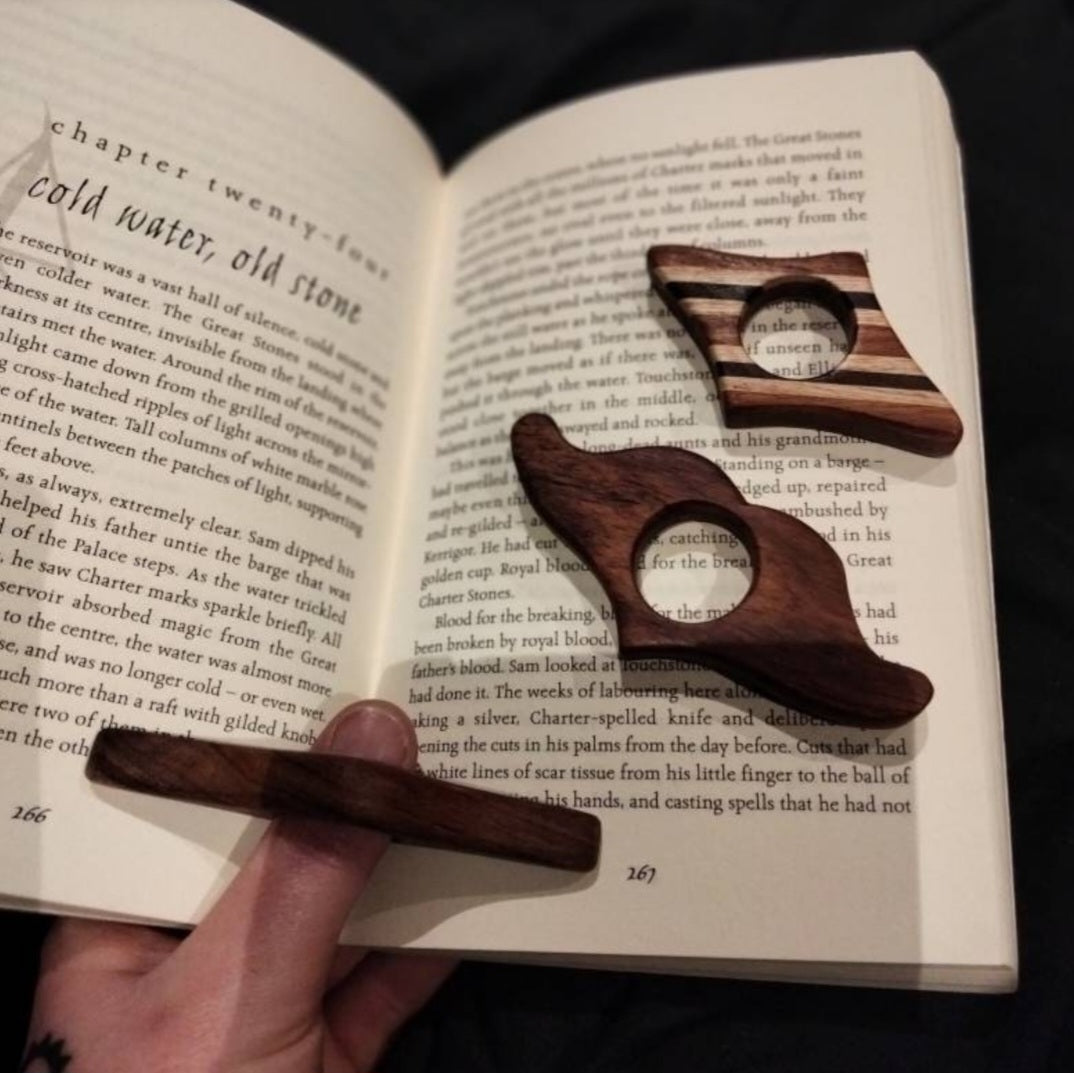 Wooden page holders shown being used in a paperback book